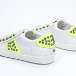 Tre quarti posteriore di BASSE bianco e giallo neon sneaker. Tomaia in pelle con borchie e suola in gomma bianca.