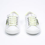 Vorderansicht des weißen und neongelben Low Top sneaker. Obermaterial aus Vollleder mit Nieten und weißer Gummisohle.
