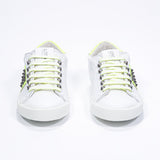 Vorderansicht des weißen und neongelben Low Top sneaker. Obermaterial aus Vollleder mit Nieten und weißer Gummisohle.