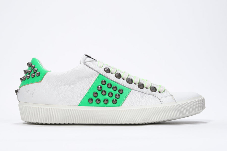 Side profile of low top white and neon green sneaker. Full leather upper with studs and white rubber sole.
