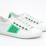 Tre quarti anteriore di BASSE bianco e verde neon sneaker. Tomaia in pelle con borchie e suola in gomma bianca.