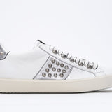 Profilo laterale di BASSE bianco e argento metallizzato sneaker. Tomaia in pelle con borchie e suola in gomma vintage.