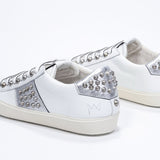 Dreiviertelansicht der Rückseite von Low Top weiß und metallic silber sneaker. Obermaterial aus Vollleder mit Nieten und Vintage-Gummisohle.