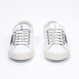 Front view of low top white and metallic rose sneaker. Full leather upper with studs and vintage rubber sole.