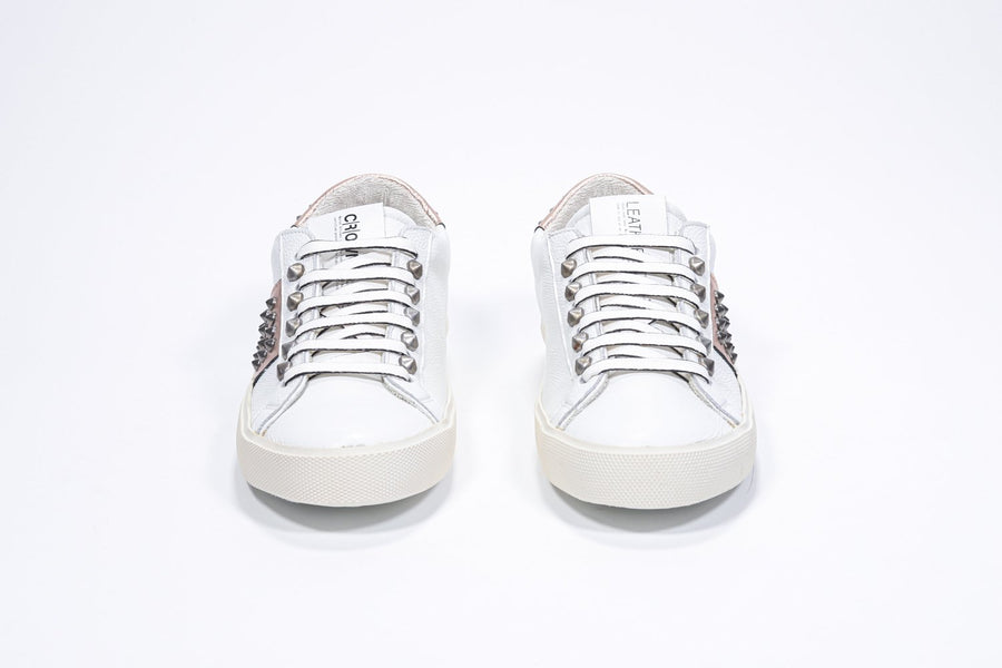 Front view of low top white and metallic rose sneaker. Full leather upper with studs and vintage rubber sole.
