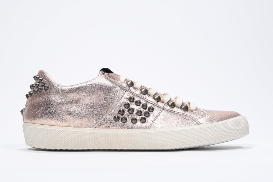 Side profile of low top metallic rose sneaker. Full leather upper with studs and vintage rubber sole.