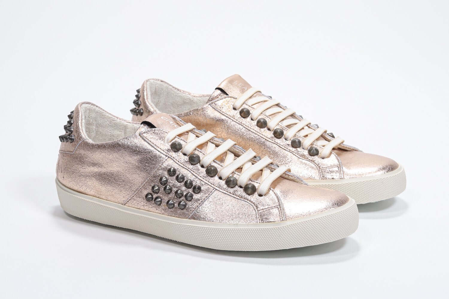 Three quarter front view of low top metallic rose sneaker. Full leather upper with studs and vintage rubber sole.