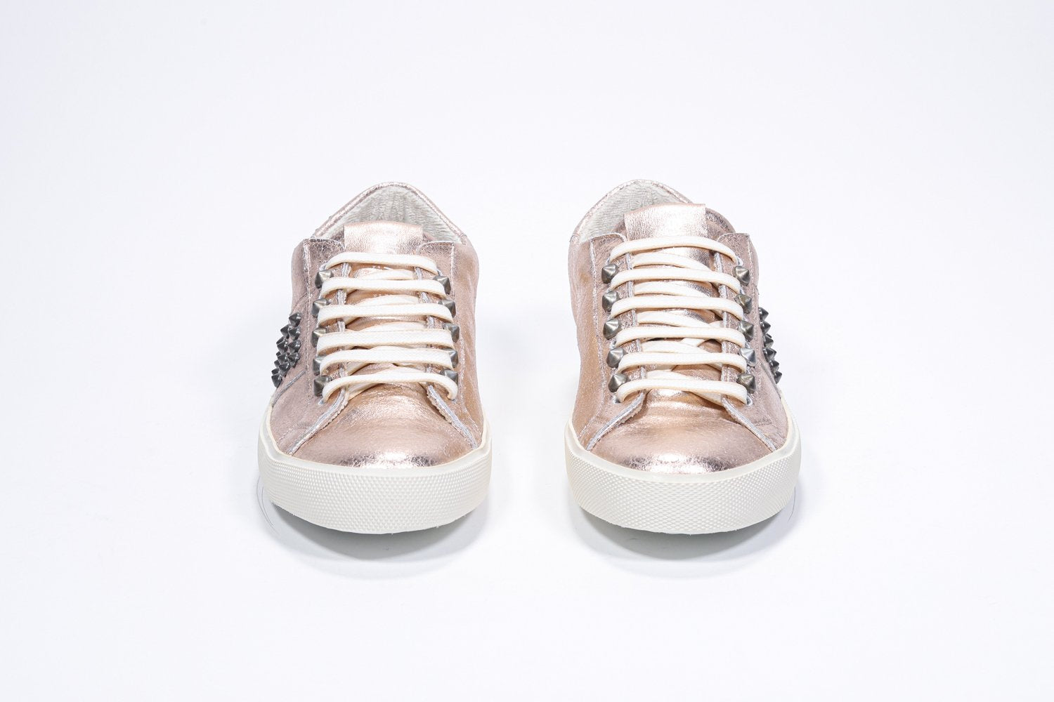 Vue de face d'une chaussure à bas prix en rose métallique sneaker. Tige en cuir avec clous et semelle en caoutchouc vintage.