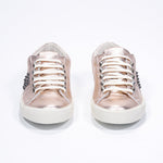 Vue de face d'une chaussure à bas prix en rose métallique sneaker. Tige en cuir avec clous et semelle en caoutchouc vintage.