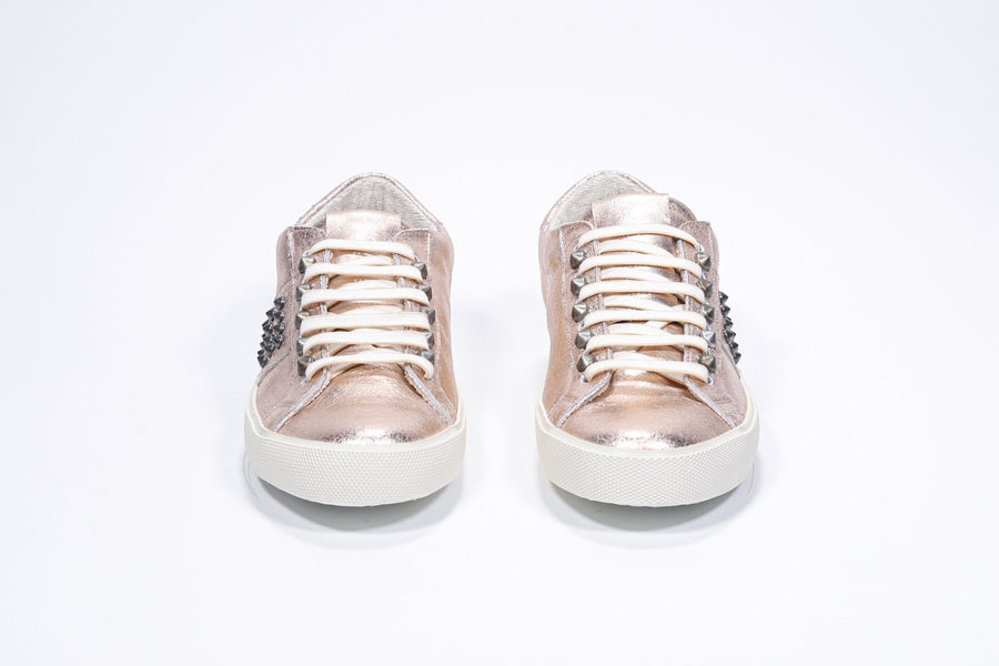 Front view of low top metallic rose sneaker. Full leather upper with studs and vintage rubber sole.