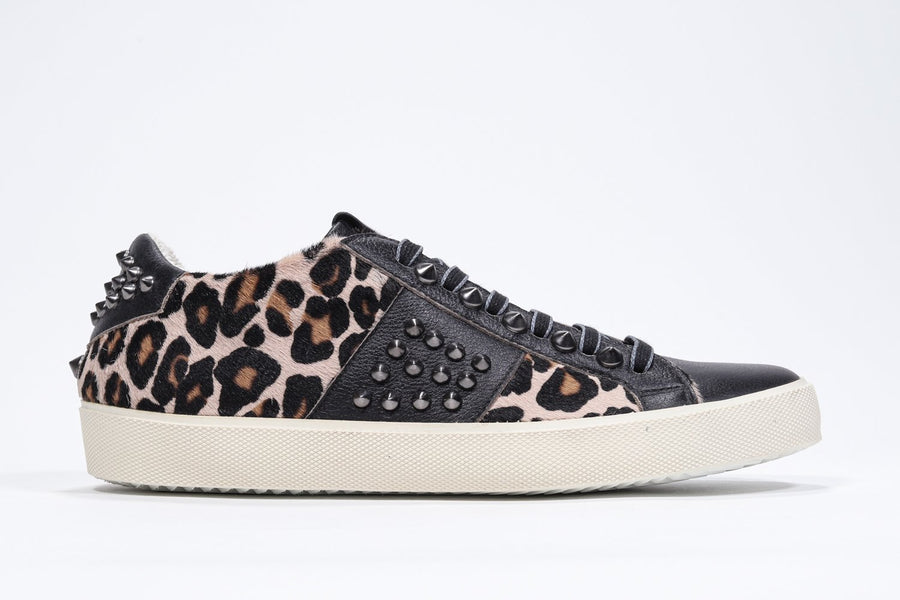 Side profile of low top leopard print sneaker. Full haircalf and leather upper with studs and vintage rubber sole.