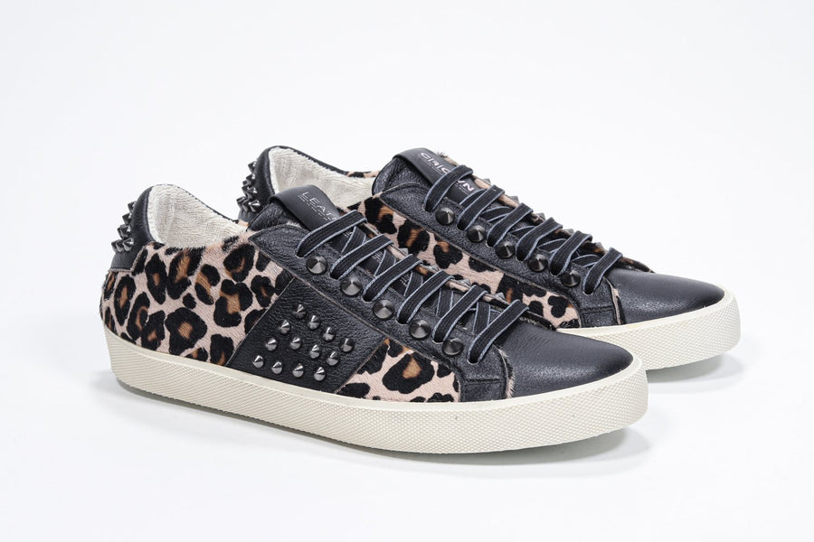 Three quarter front view of low top leopard print sneaker. Full haircalf and leather upper with studs and vintage rubber sole.