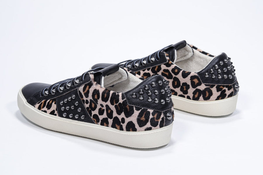 Three quarter back view of low top leopard print sneaker. Full haircalf and leather upper with studs and vintage rubber sole.