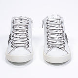 Vista frontale della mid top bianca sneaker. Tomaia in pelle con borchie, zip interna e suola in gomma vintage.