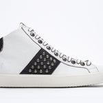 Side profile of mid top white and black sneaker. Full leather upper with studs, an internal zip and vintage rubber sole.