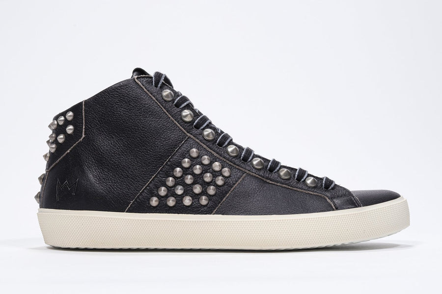 Side profile of mid top black sneaker. Full leather upper with studs, an internal zip and vintage rubber sole.