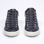 Front view of mid top black sneaker. Full leather upper with studs, an internal zip and vintage rubber sole.