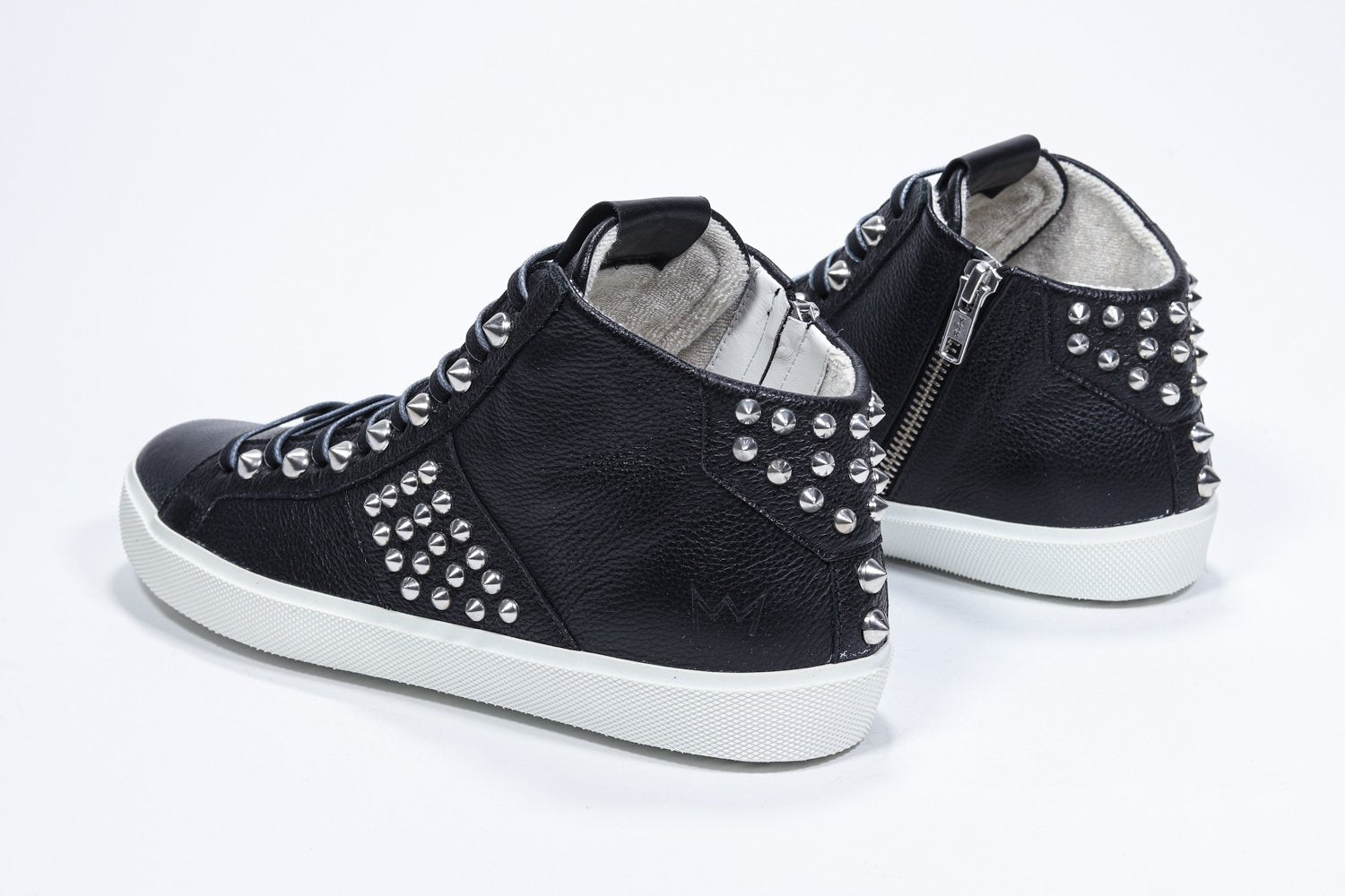 Vista posteriore di tre quarti del modello mid top nero sneaker. Tomaia in pelle con borchie, zip interna e suola in gomma bianca.