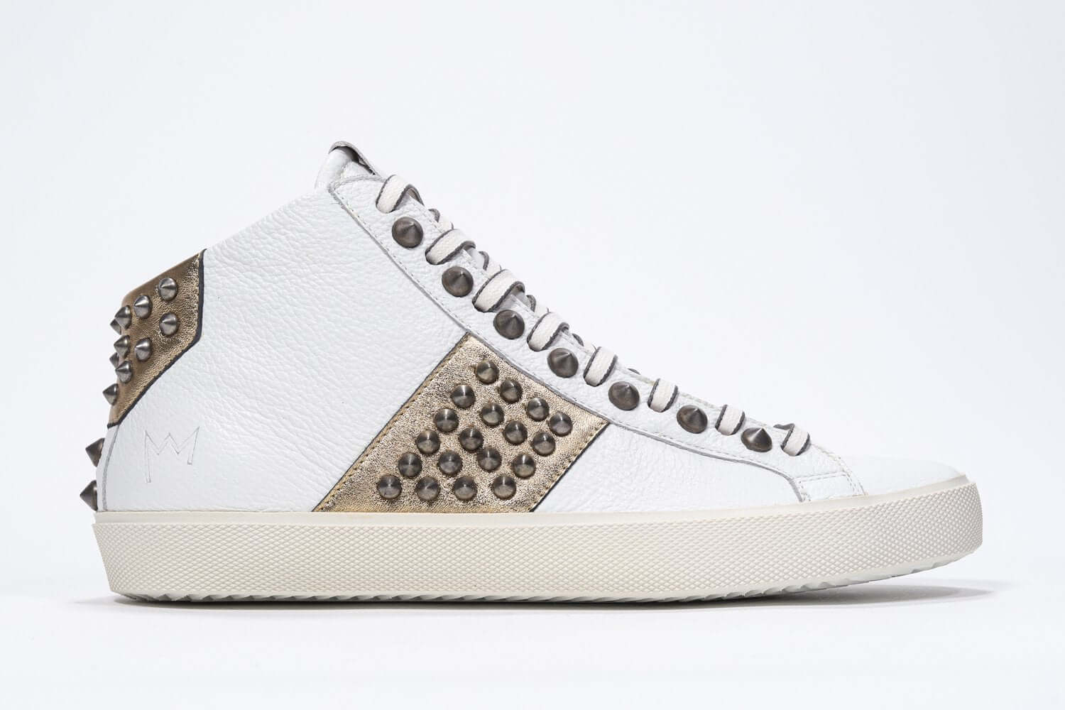 Side profile of mid top white and metallic gold sneaker. Full leather upper with studs, an internal zip and vintage rubber sole.