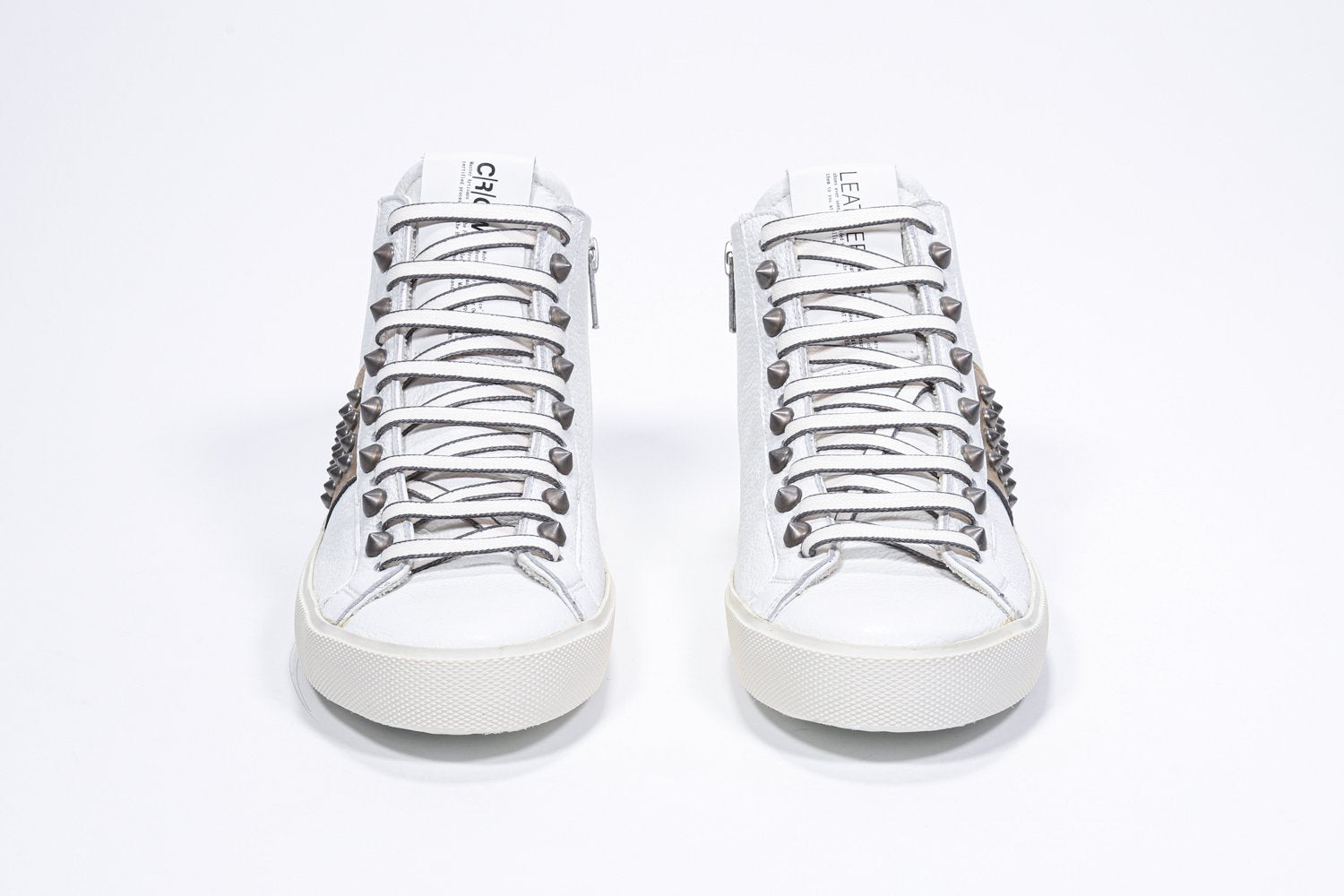 Vue de face d'un modèle intermédiaire blanc et or métallisé sneaker. Tige en cuir avec clous, fermeture à glissière intérieure et semelle en caoutchouc vintage.
