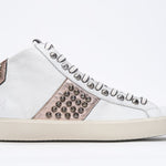 Profilo laterale di mid top bianco e rosa metallizzato sneaker. Tomaia in pelle con borchie, zip interna e suola in gomma vintage.