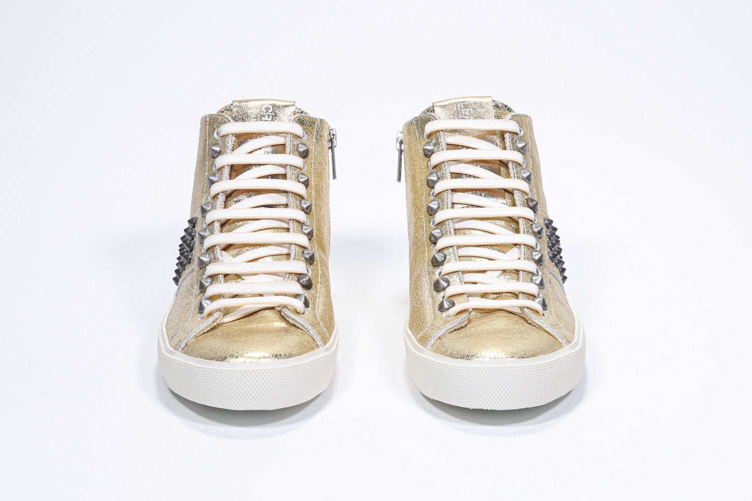 Vista frontale del modello mid top in oro metallizzato sneaker. Tomaia in pelle con borchie, zip interna e suola in gomma vintage.