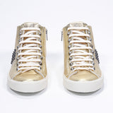 Front view of mid top metallic gold sneaker. Full leather upper with studs, an internal zip and vintage rubber sole.