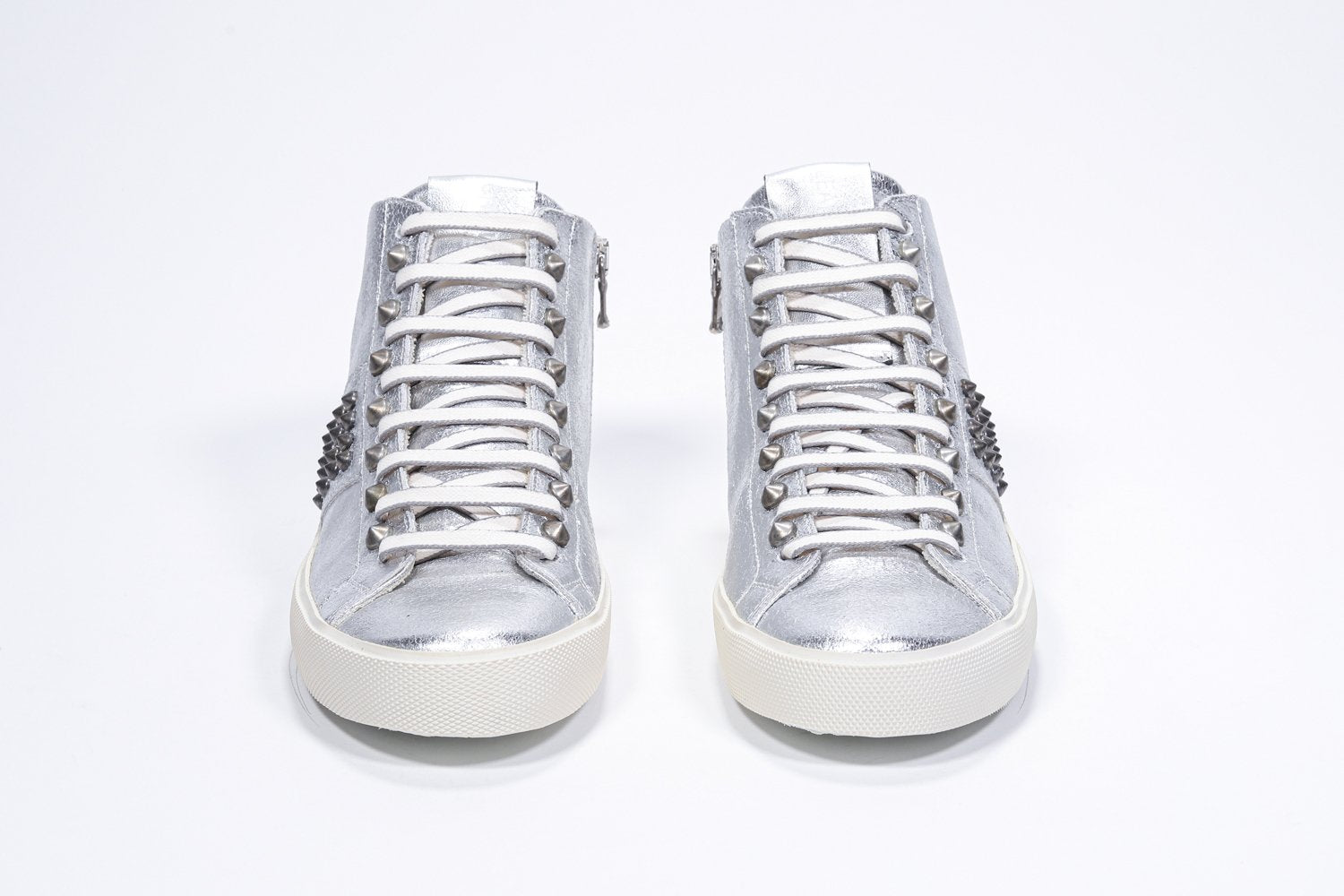 Vue de face de la chaussure intermédiaire en argent métallisé sneaker. Tige en cuir avec clous, fermeture éclair intérieure et semelle en caoutchouc vintage.