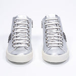 Front view of mid top metallic silver sneaker. Full leather upper with studs, an internal zip and vintage rubber sole.