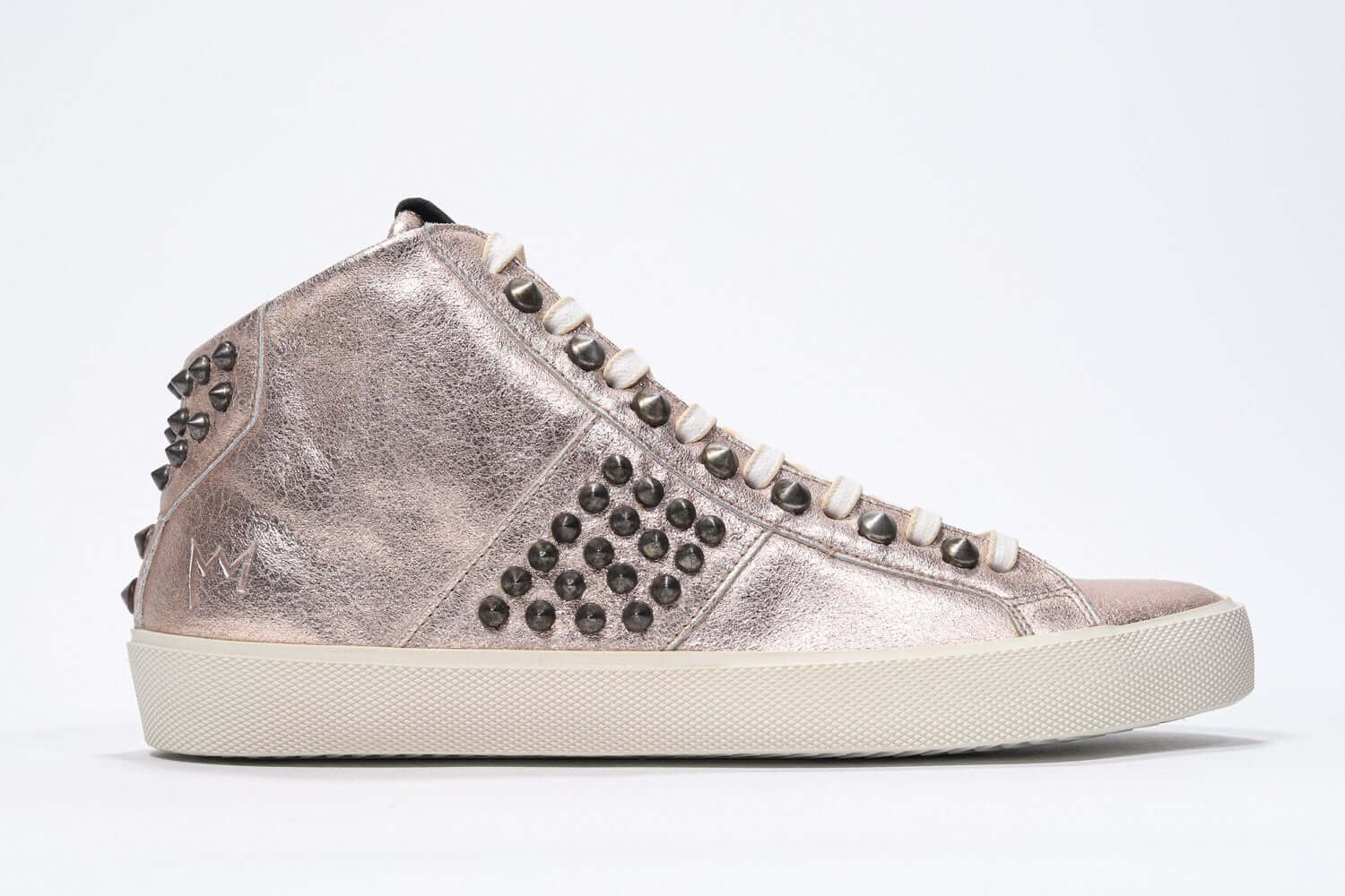 Profil latéral d'une rose métallique à mi-hauteur sneaker. Tige en cuir avec clous, fermeture éclair intérieure et semelle en caoutchouc vintage.