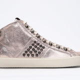 Side profile of mid top metallic rose sneaker. Full leather upper with studs, an internal zip and vintage rubber sole.