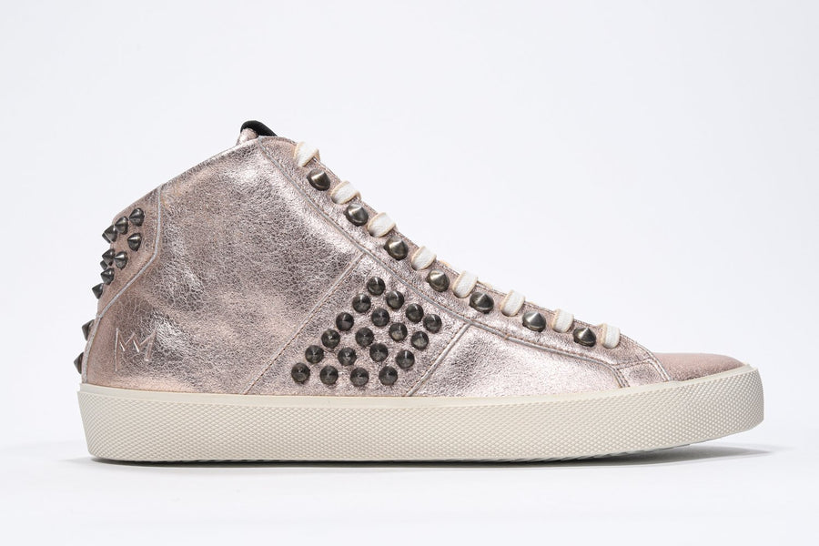 Side profile of mid top metallic rose sneaker. Full leather upper with studs, an internal zip and vintage rubber sole.