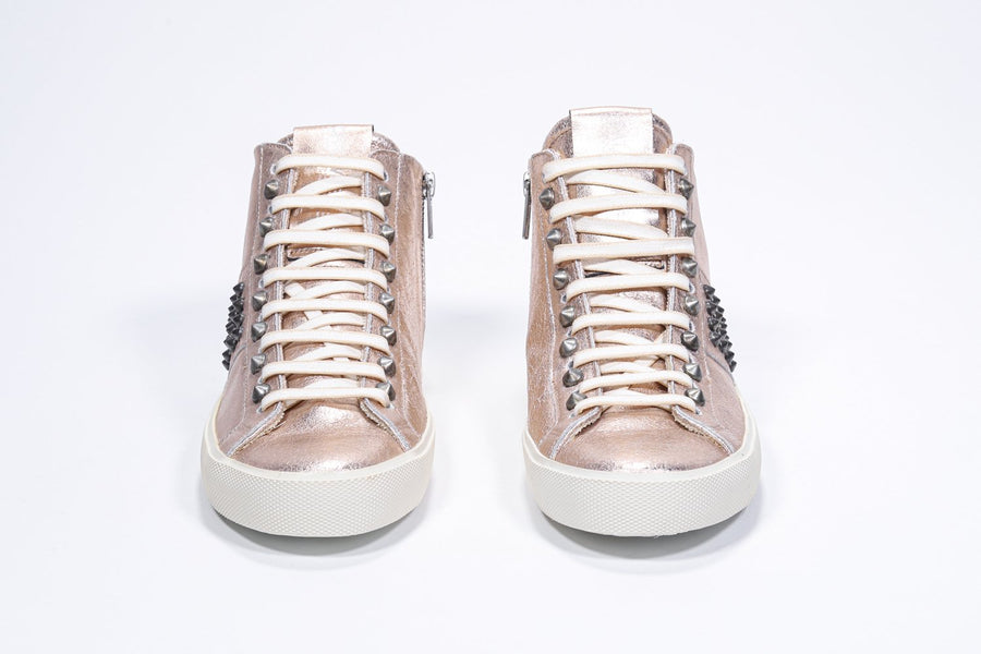 Front view of mid top metallic rose sneaker. Full leather upper with studs, an internal zip and vintage rubber sole.