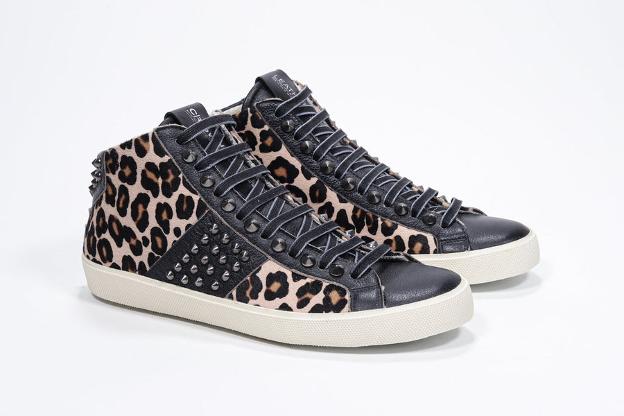 Three quarter front view of mid top leopard print sneaker. Haircalf and leather upper with studs, an internal zip and vintage rubber sole.