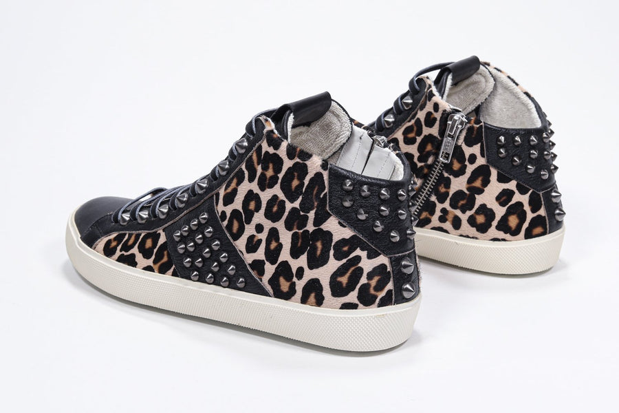 Three quarter back view of mid top leopard print sneaker. Haircalf and leather upper with studs, an internal zip and vintage rubber sole.