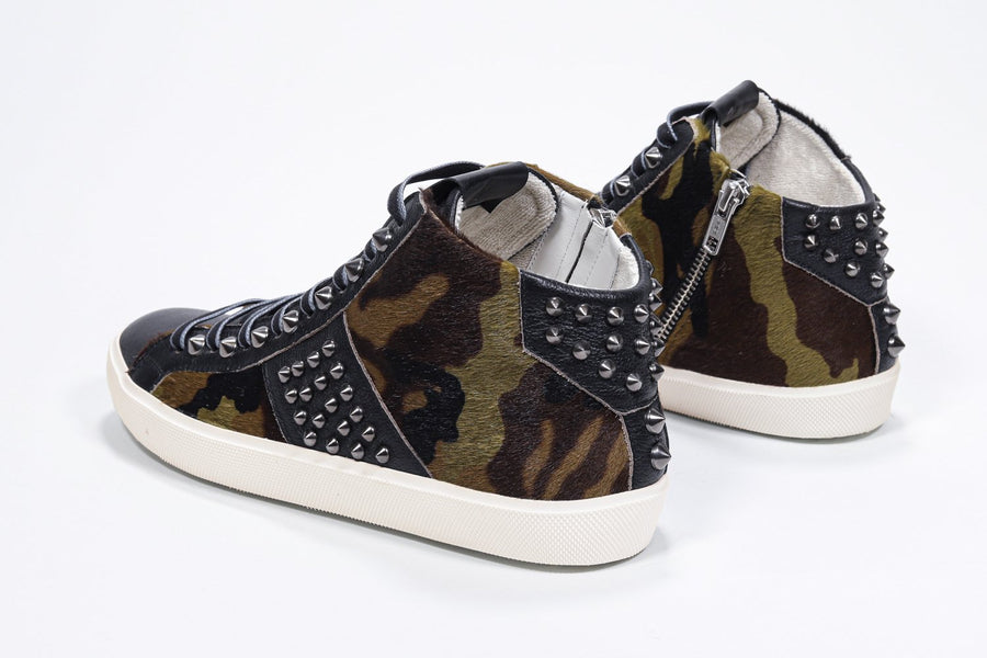 Three quarter back view of mid top camouflage print sneaker. Haircalf and leather upper with studs, an internal zip and vintage rubber sole.