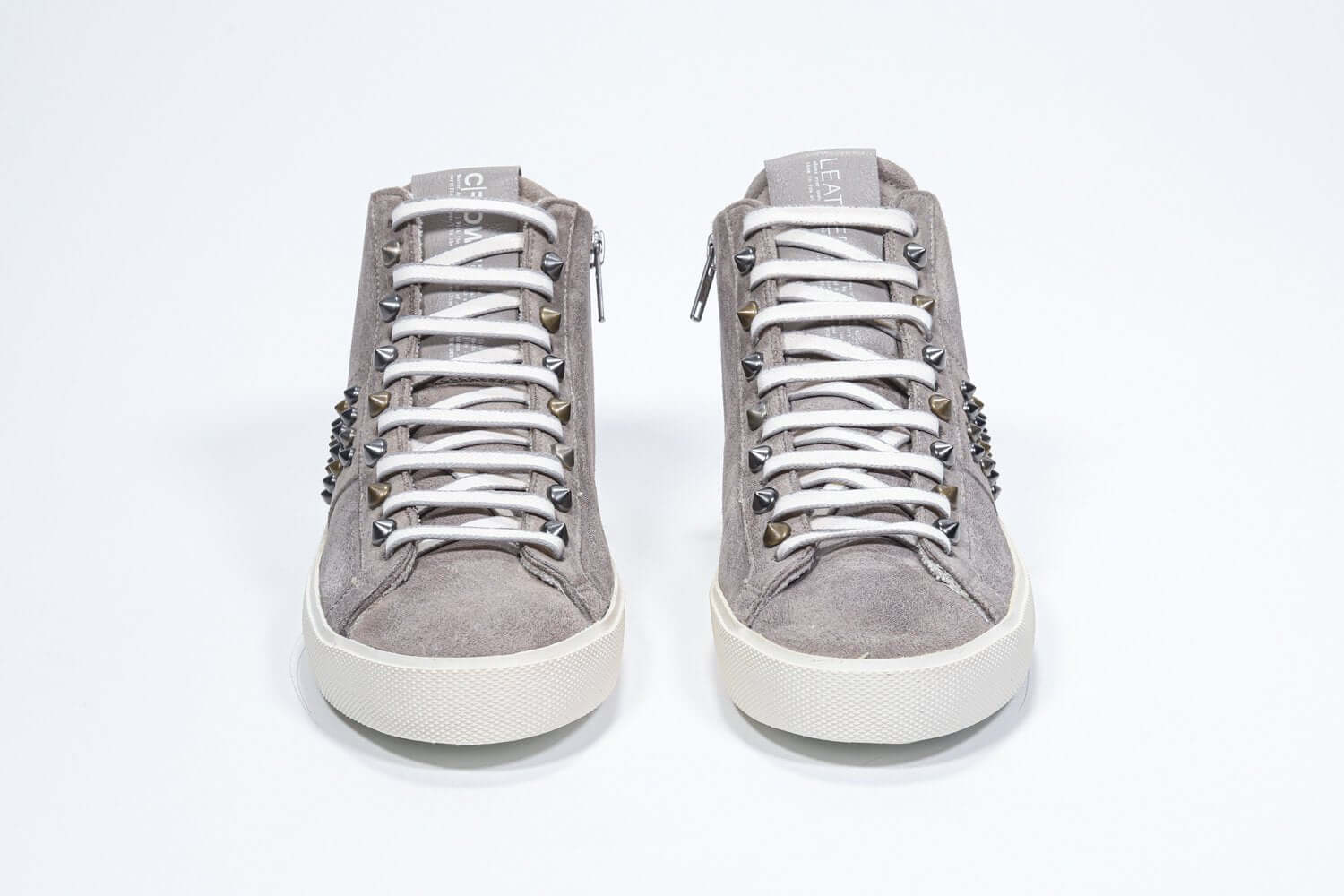 Vue de face de la chaussure intermédiaire de couleur beige sneaker. Tige en daim avec clous, fermeture à glissière intérieure et semelle en caoutchouc vintage.