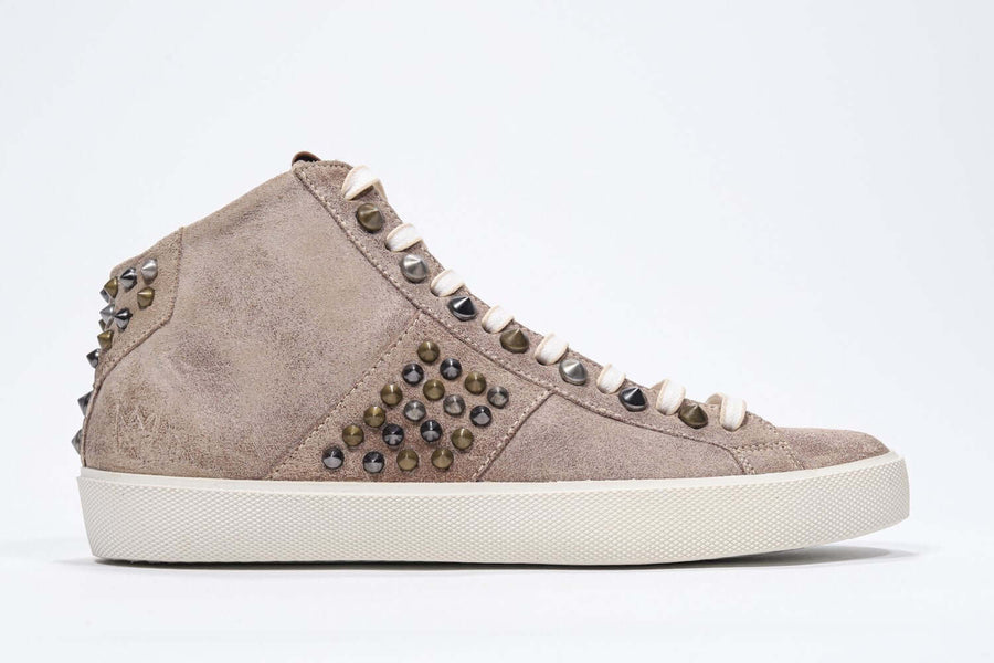 Side profile of mid top cuoio color sneaker. Full suede upper with studs, an internal zip and vintage rubber sole.