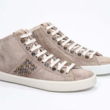 Three quarter front view of mid top cuoio color sneaker. Full suede upper with studs, an internal zip and vintage rubber sole.