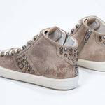Three quarter back view of mid top cuoio color sneaker. Full suede upper with studs, an internal zip and vintage rubber sole.