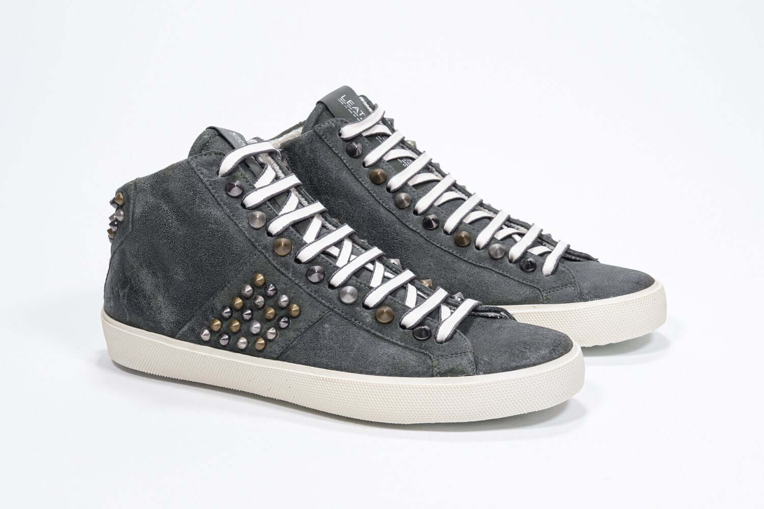 Three quarter front view of mid top khaki sneaker. Full suede upper with studs, an internal zip and vintage rubber sole.