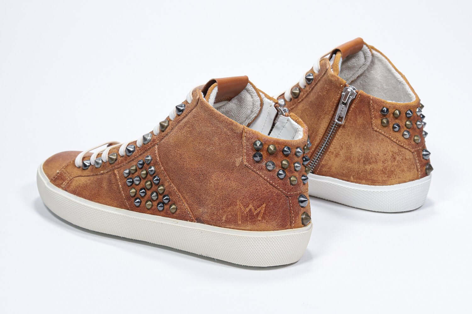 Three quarter back view of mid top rust color sneaker. Full suede upper with studs, an internal zip and vintage rubber sole.