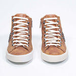 Front view of mid top rust color sneaker. Full suede upper with studs, an internal zip and vintage rubber sole.