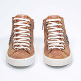 Front view of mid top rust color sneaker. Full suede upper with studs, an internal zip and vintage rubber sole.