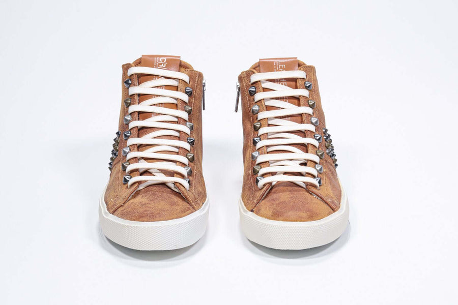 Front view of mid top rust color sneaker. Full suede upper with studs, an internal zip and vintage rubber sole.