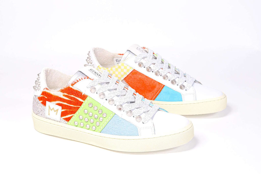 Three quarter front view of low top sneaker. Patchwork upper of mixed materials and silver studs.