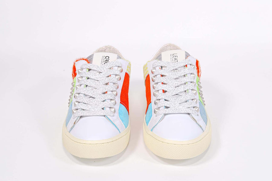 Front view of low top sneaker. Patchwork upper of mixed materials and silver studs.