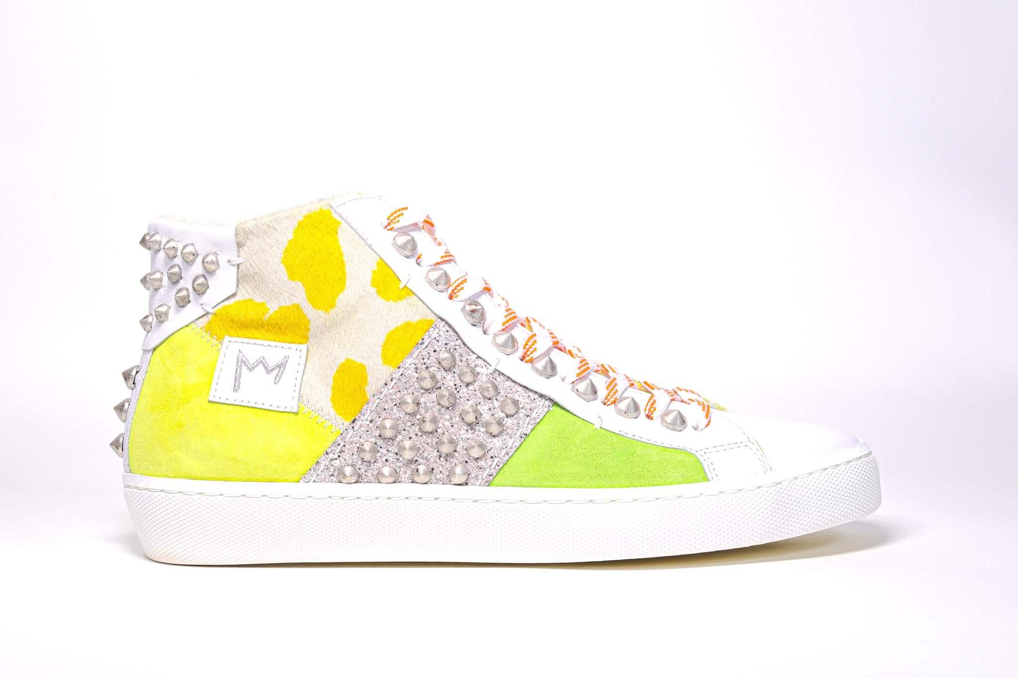 Side profile of mid top sneaker. Patchwork upper of mixed materials and silver studs.