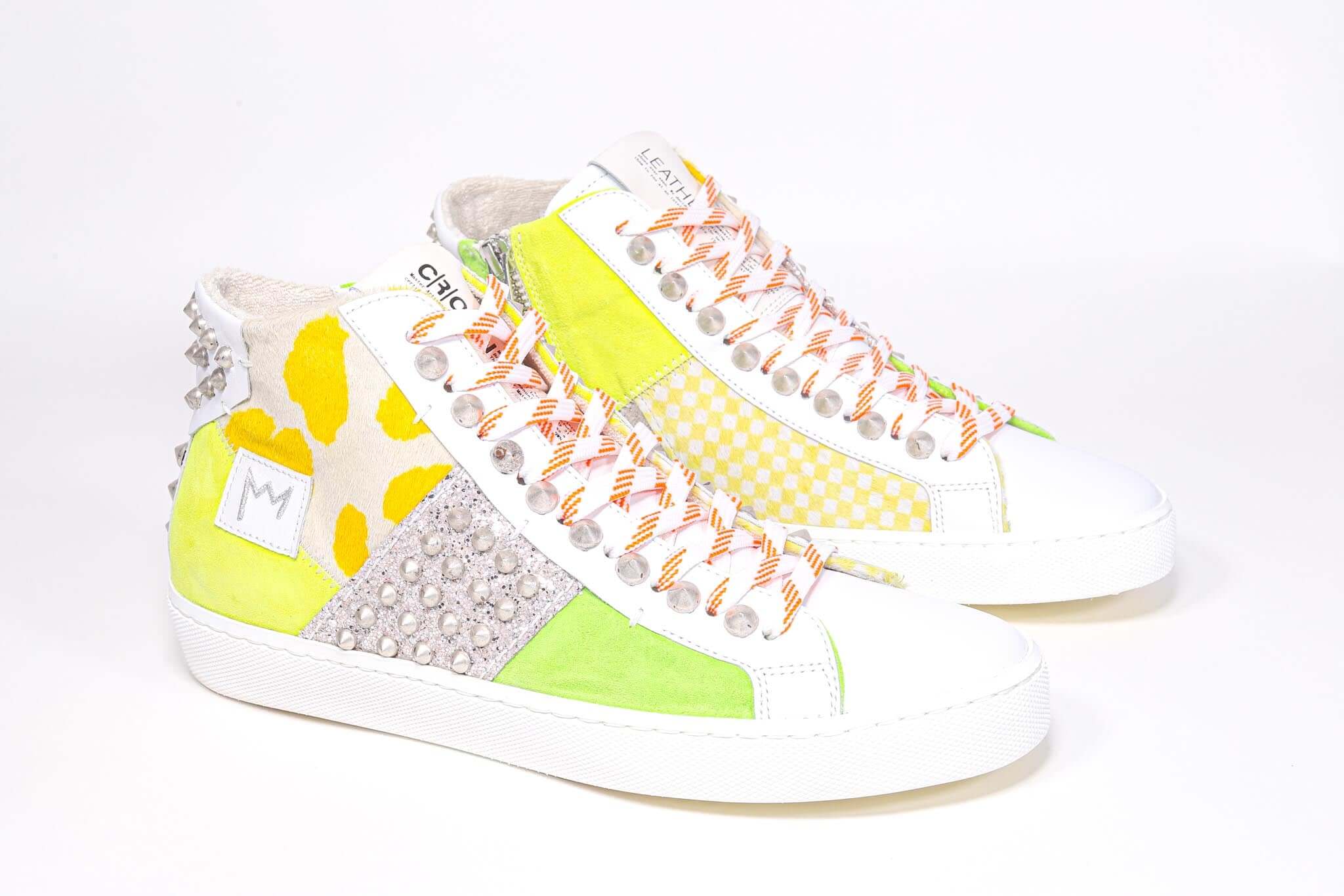 Three quarter front view of mid top sneaker. Patchwork upper of mixed materials and silver studs.