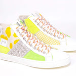 Three quarter front view of mid top sneaker. Patchwork upper of mixed materials and silver studs.